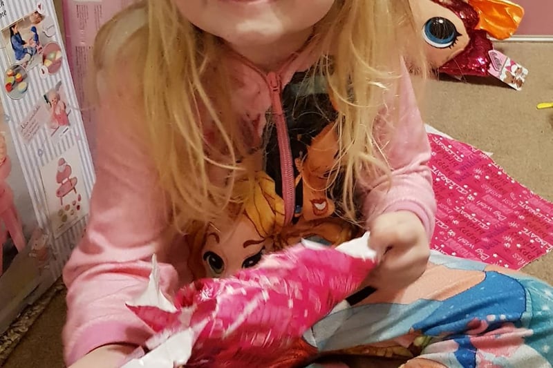 Stace Gilham's daughter makes a 'say cheese' face while unwrapping her special presents on her lockdown birthday.
