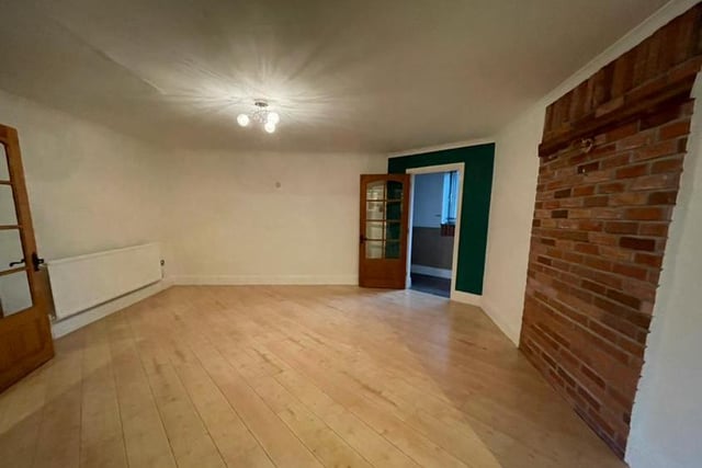 Here is the property's dining room, complete with wood-effect flooring and exposed feature brickwork. There is a central heating radiator and also open-plan access to the kitchen.