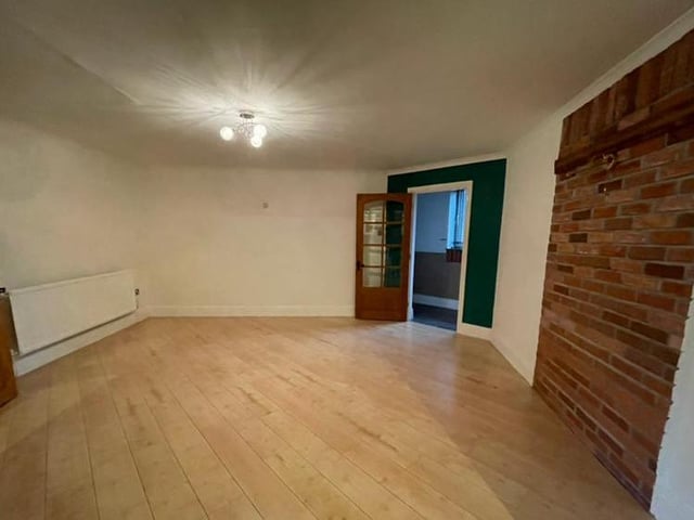 Here is the property's dining room, complete with wood-effect flooring and exposed feature brickwork. There is a central heating radiator and also open-plan access to the kitchen.