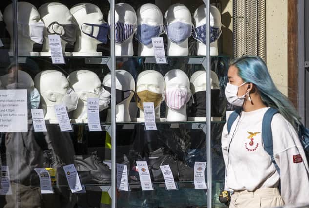 A woman wearing a protective face mask walks past a shop selling masks. Pic: Jane Barlow/PA Wire