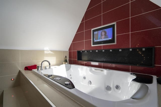 The bathroom has a feature inset Jacuzzi style bath with television.