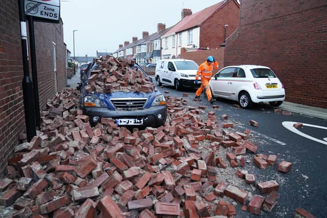 A man makes safe fallen masonry from a property, which has damaged a nearby car, on Gloucester Avenue in Roker, Sunderland, after gusts of almost 100 miles per hour battered some areas of the UK during Storm Arwen. Picture date: Saturday November 27, 2021.