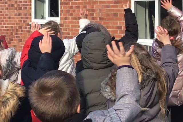 Pupils waving at residents in Thornbury Care Centre after delivering their kindness cards and cakes.