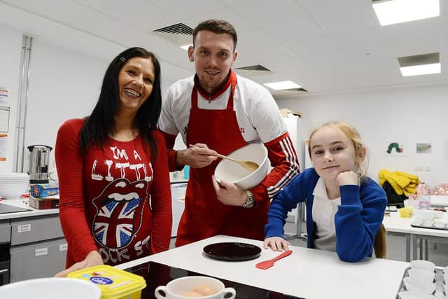 Sunderland AFC striker Charlie Wyke baking a cake with support from Debbie Dunne and her granddaughter Charlie D Kennedy during the EFL Day of Action held at the Beacon of Light