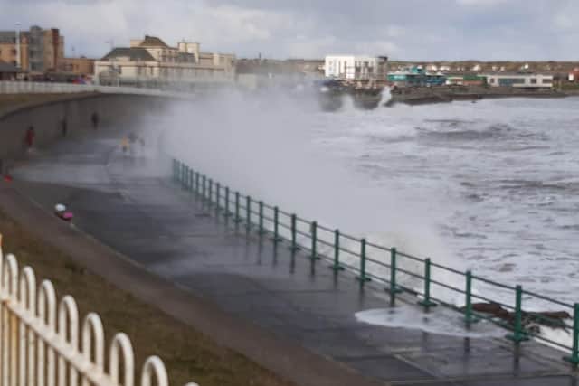 Waves crash over the promenade