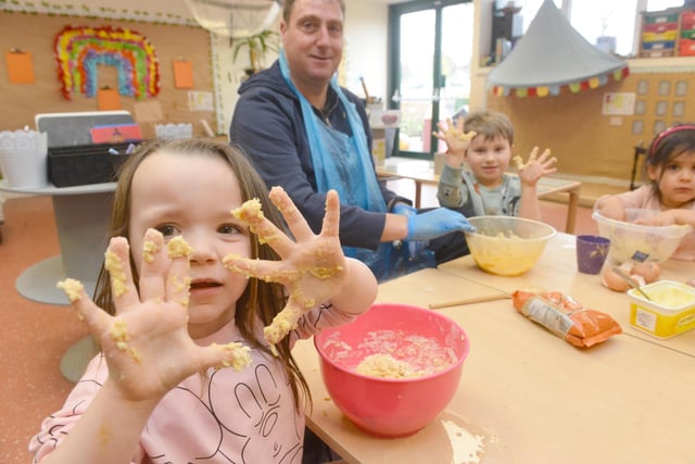 Children show off their hands covered in cake mix.