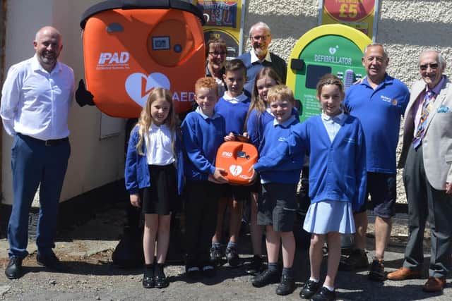 Representatives from the East Rainton Community Group, Hetton Rotary, and the village shop join East Rainton Primary School children to officially unveil the new defibrillator