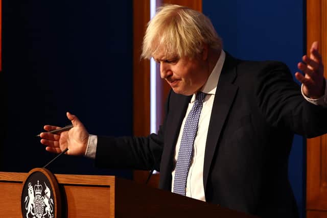Prime Minister Boris Johnson gestures whilst speaking at a press conference in London's Downing Street after ministers met to consider imposing new restrictions in response to rising cases and the spread of the Omicron variant.