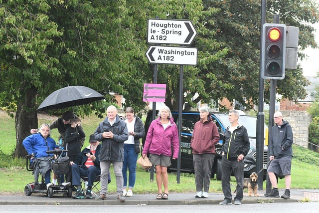 Crowds at Newbottle take shelter against the rain as they wait the Tour of Britain cyclists.