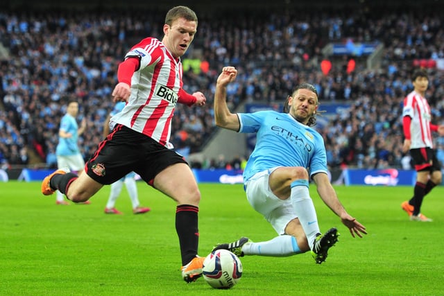 Sunderland's English midfielder Craig Gardner (L) tries to cross as Manchester City's Argentinian defender Martin Demichelis (R) slides in to block during the League Cup final football match between Manchester City and Sunderland at Wembley Stadium in London on March 2, 2014.