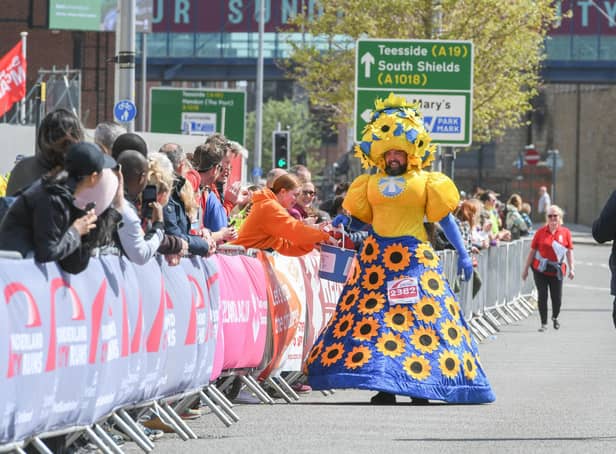 Colin Burgin-Plews dressed in a giant sunflower dress as he approaches the finish line.