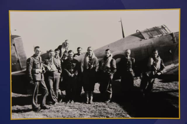 Flight Lieutenant Francis Blackadder (centre) with other pilots and ground crew leaning against one of the Squadrons Hawker Hurricane fighters.