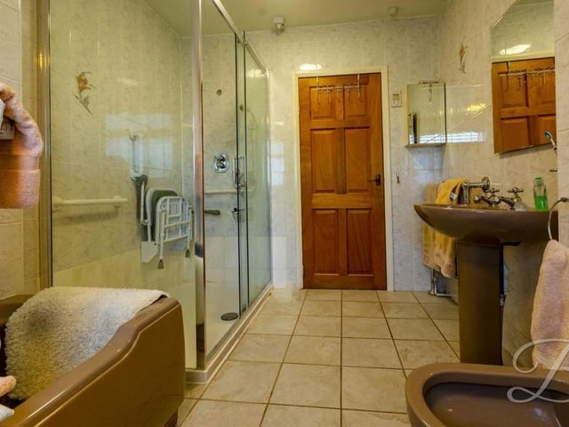 Another shot of the bathroom, showing the large walk-in shower. There is also a central heating radiator and an opaque window into the conservatory.