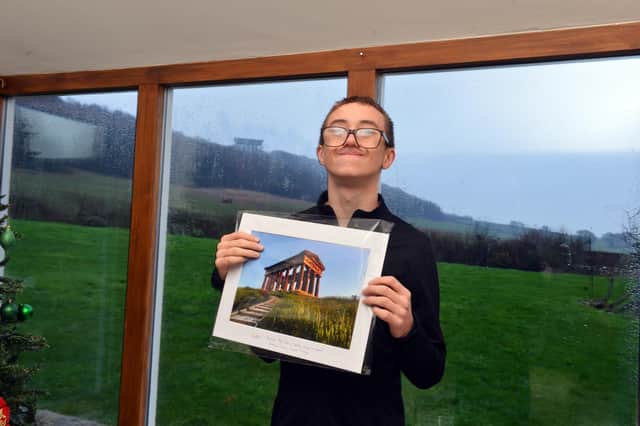 Hugh Clinton's shows off one of his 70,000 pictures of Penshaw Monument, with the real thing behind him.