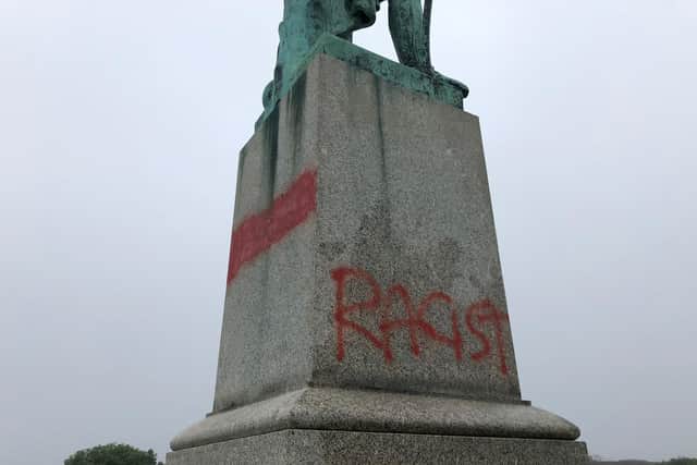 The words 'parasite' and 'racist' have been written on the statue.