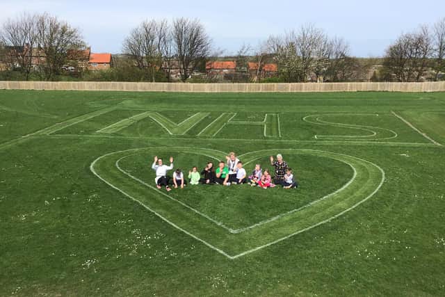 Children and staff from the Ribbon Academy in Murton with the NHS symbol on their field.