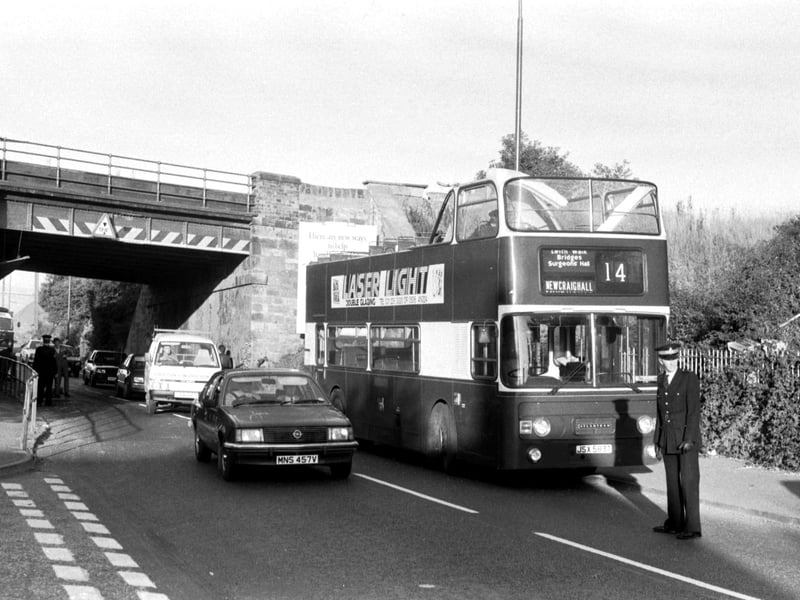 A policeman stands beside a no 14 Lothian Region Transport bus which had its roof ripped off passing under a low bridge at Newcraighall Road in Edinburgh, September 1986.