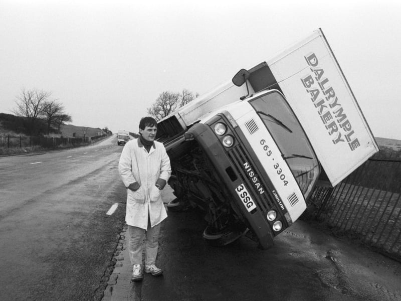 Driver Gregor Maclean stands beside his Dalrymple Bakery van, blown over in Braid Hills Road Edinburgh during the gales in December 1986.