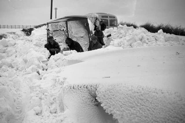 Men are hidden by giant drifts as they try to dig out a stranded bus and van.