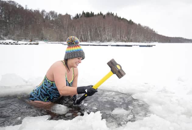 Alice Goodridge, from Newtonmore, uses a sledgehammer to create a channel in the ice to swim in Loch Insh, in the Cairngorms National Park.