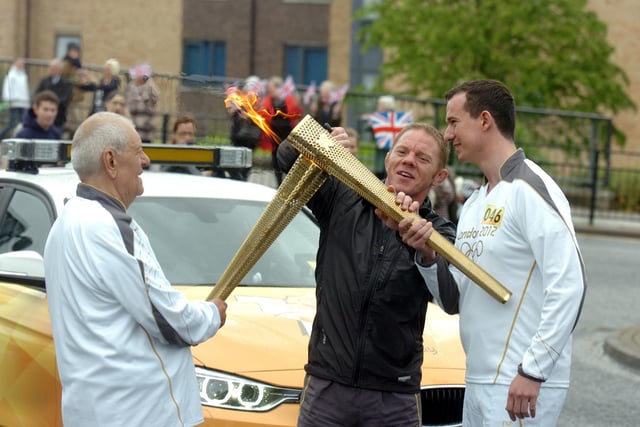 John Wheatan passes on the flame to Mark Turnbull, right, on High Street West.