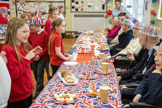 Children from Plains Farm Academy enjoy a Coronation tea chat with residents from the Village Care Home.