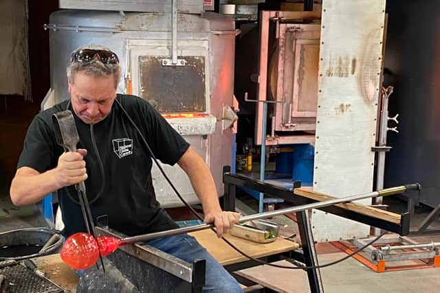 Glassmaker Ian Spence blowing air into the glass in the Hot Glass Studio