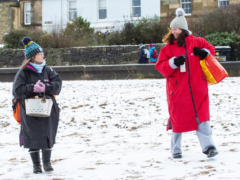 Maree Rudd (black robe) and Isabella McNamara (red robe) head to the snowy beach for a dip