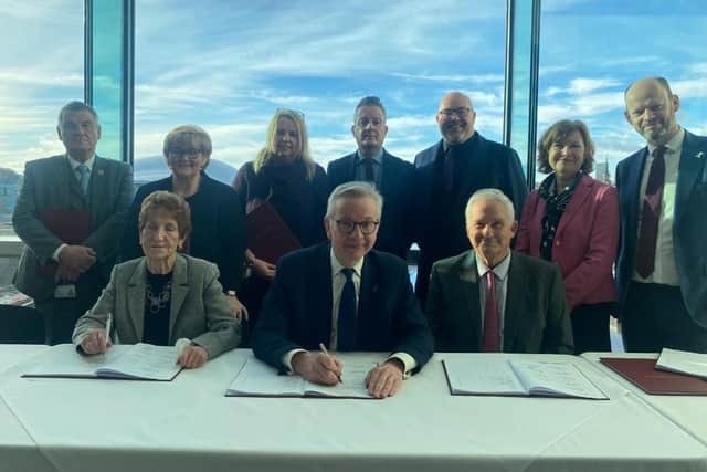 Mr Gove signs the deal, flanked by local leaders including Coun Tracy Dixon (back row, second left), Coun Graeme Miller (back row, fifth left) and Coun Glen Sanderson (front right)