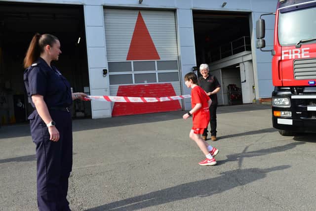 William Young crosses the finishing line at Farringdon Community Fire Station as the tape is held by Lynsey McVay, Assistant Chief Fire officer Tyne and Wear Fire Service, and Sylvia Stoneham, from Fire Fighters charity. Picture by Frank Reid