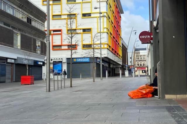 A homeless person sits on an empty Market Square as coronavirus lockdown measures leave the city empty