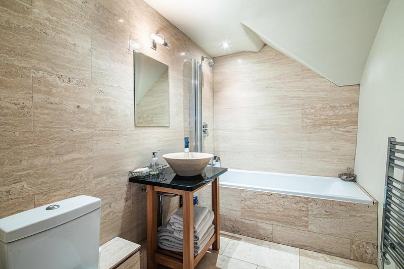 The fully tiled main bathroom features a bath and shower, and recessed lighting.