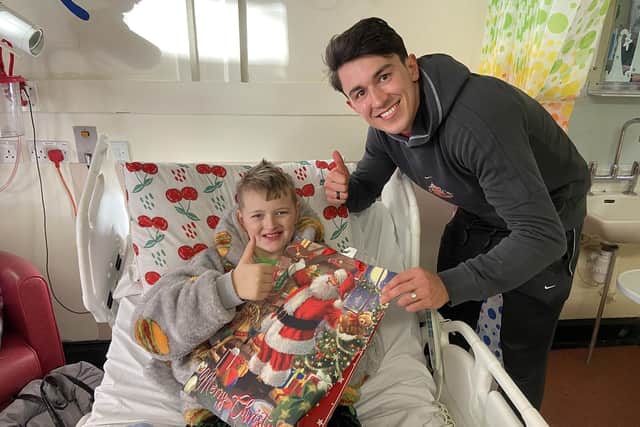 Luke O'Nien handing over a goody bag to Rhys Carr, 11, during a visit to the children's ward at Sunderland Royal Hospital. 

Picture by FRANK REID