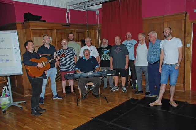 Marty Longstaff, on guitar, guides Sunderland Male Voice Choir through his song.
