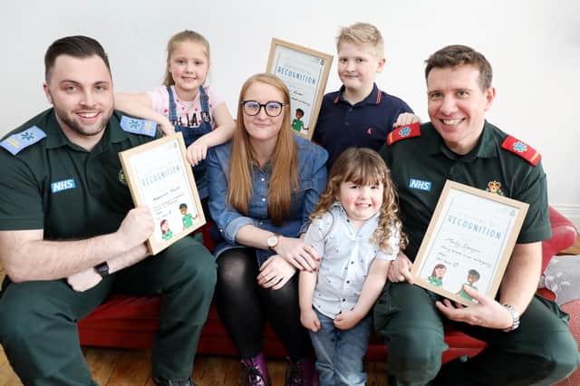 Student paramedic Louis Smart, left, and paramedic Andy Wilson, right, present bravery awards to Alex, Sebastian and Monty with mum Lucy.