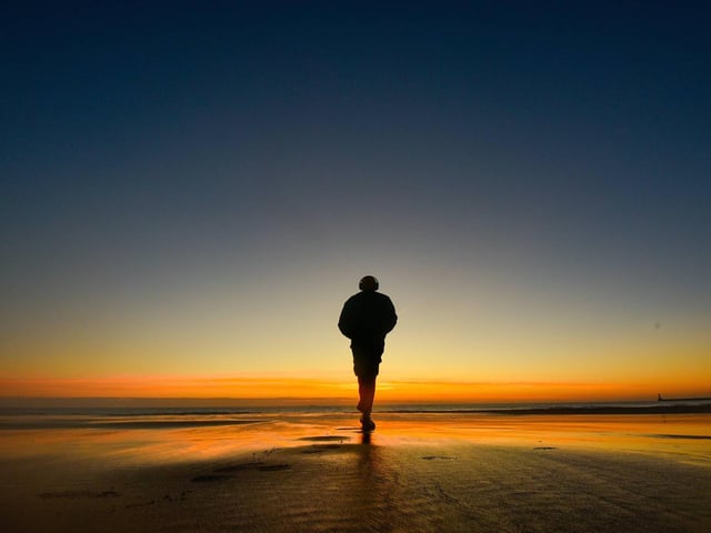 A walker heads across the beach.
