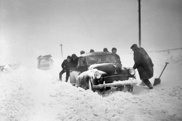 Workmen battle to clear a car from the snow in 1963.