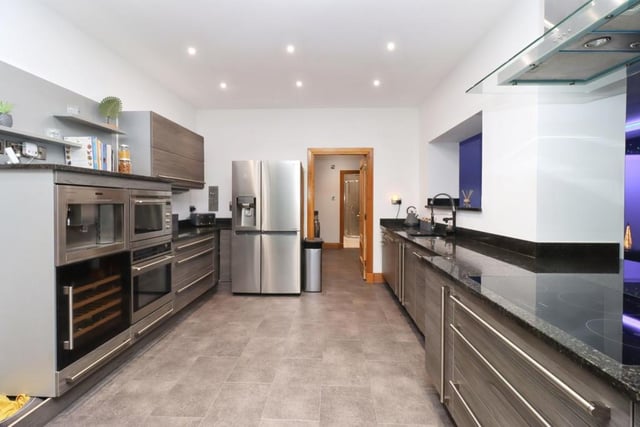 Immaculate fitted kitchen with top of the range appliances, induction hob and stainless steel extractor, ample base and wall mounted units, and contrasting granite worktops.