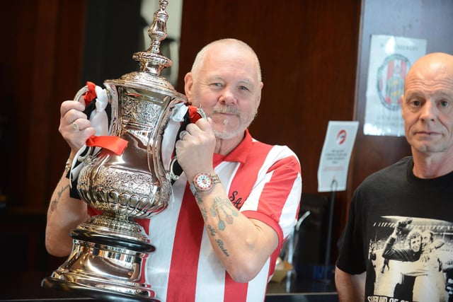 A supporter holds a replica of the FA Cup.