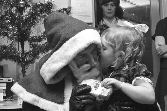 Santa received a kiss and a present from three year Louise Cape for going along to Farringdon playgroup's Christmas party to present gifts  to the children in 1976.