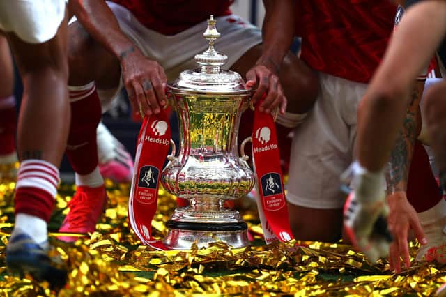 LONDON, ENGLAND - AUGUST 01: Detailed view of the FA Cup Trophy as it sits in the pitch surrounded by Arsenal players after the FA Cup Final match between Arsenal and Chelsea at Wembley Stadium on August 01, 2020 in London, England.
