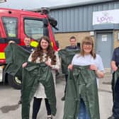 Steph Archbold and Gillian Pickles of Love, Amelia are pictured with Mark Stewart, Kyle Shaw and Andrew Lane of TWFRS outside of the charities offices holding examples of the donated waterproof clothing.