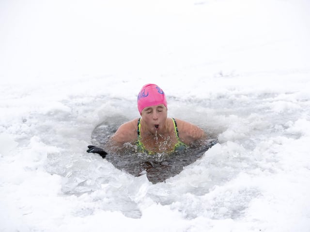 Alice Goodridge, from Newtonmore, plunges through a hole in the ice in Loch Insh, in the Cairngorms National Park.