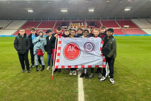 Thornhill Academy pupils with their flag on the Stadium of Light pitch.