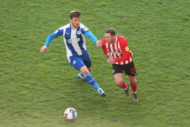 WIGAN, ENGLAND - APRIL 13: Aiden McGeady of Sunderland battles for possession with Lee Evans of Wigan Athletic during the Sky Bet League One match between Wigan Athletic and Sunderland at DW Stadium on April 13, 2021 in Wigan, England. Sporting stadiums around the UK remain under strict restrictions due to the Coronavirus Pandemic as Government social distancing laws prohibit fans inside venues resulting in games being played behind closed doors. (Photo by Lewis Storey/Getty Images)