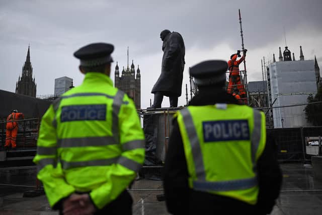Police look on as workers uncover the statue of Winston Churchill in Parliament Square on June 17, after it was covered up to protect it from vandalism over the previous weekend.