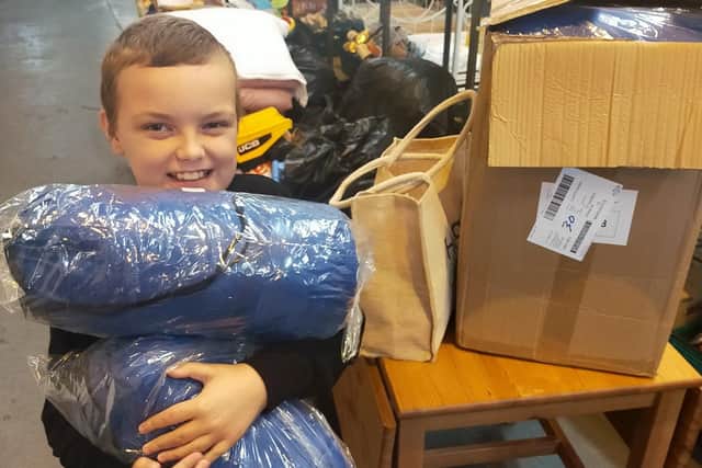 10-year-old Aaron Stubbs with some of the sleeping bags purchased for homeless people who visit the soup kitchen