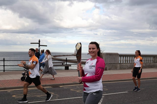 Katie Williamson takes the baton past Roker lighthouse as the Queen's Baton Relay goes along Sunderland's seafront.