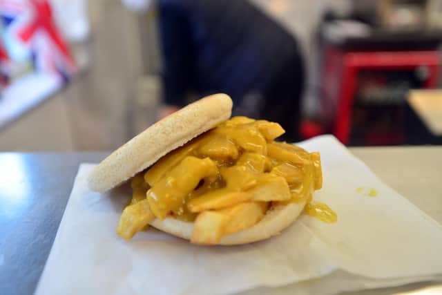 A bun is filled with chips and covered in curry sauce before it is dipped in batter and fried.