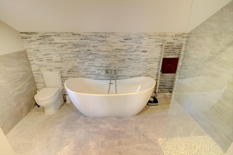The ensuite, which drops down two steps, boasts attractive quartz tiling behind a free-standing designer style double ended bath and a separate lift-off shower unit.
